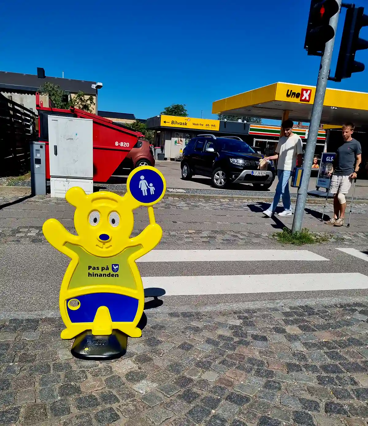 Trafik Bjørn ved tankstation. Sikker vej for skoleelever. Gul Trafik Bjørn fra Brave.
